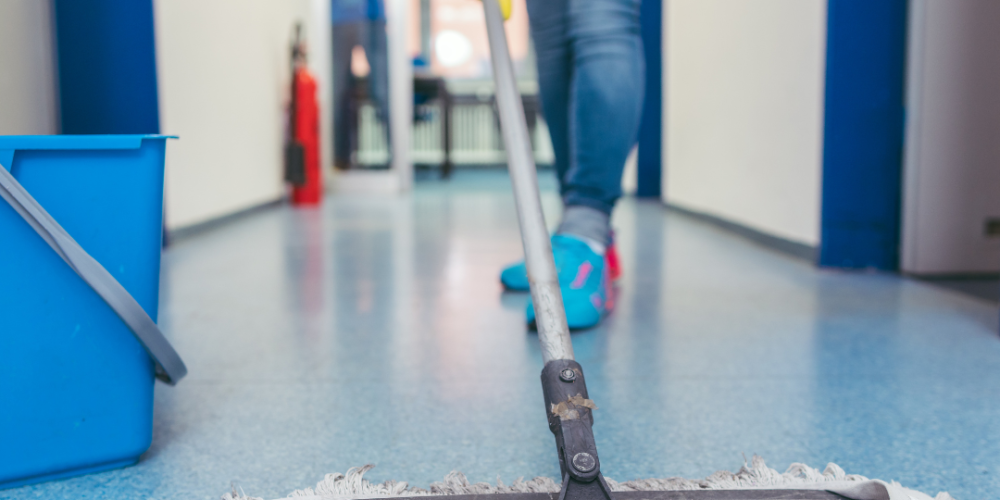 Person moping the floor with. a clean mop and yellow rubber gloves