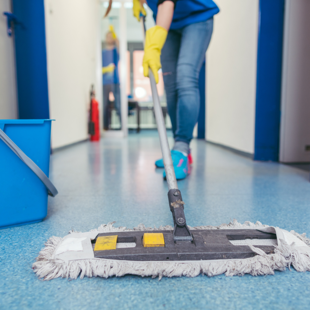 Person moping the floor with. a clean mop and yellow rubber gloves