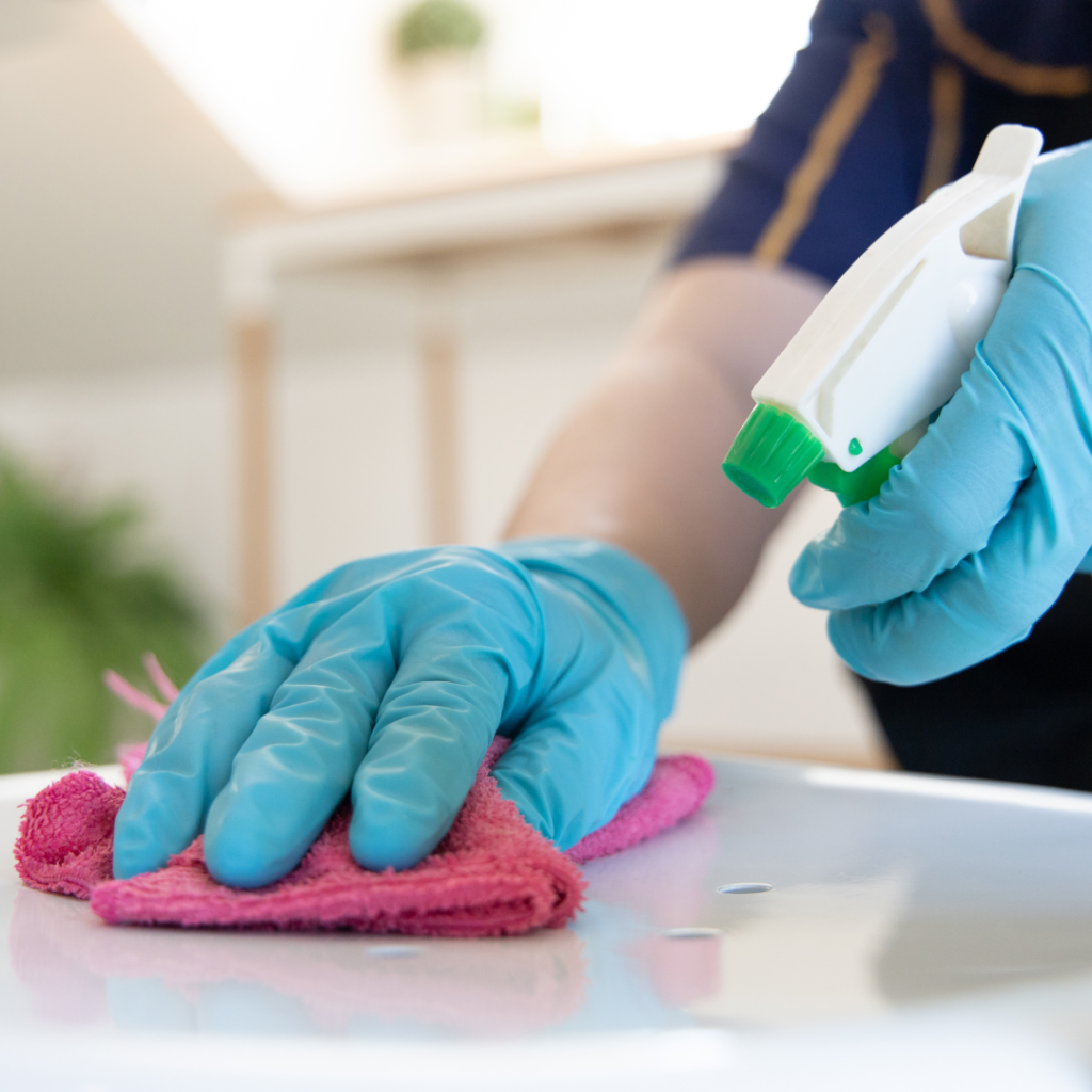 Person cleaning wearing blue gloves and a pink cloth
